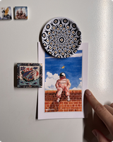 Whimsical astronaut-on-a-brick-wall postcard held on a fridge by magnets