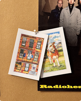 Brownstone facade and meadow cow postcards pinned to a cork board