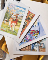 A fanned-out stack of hand-painted postcards spread on a desk