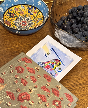 Folk-art bird postcard beside an ornate floral bowl and a bowl of blackberries