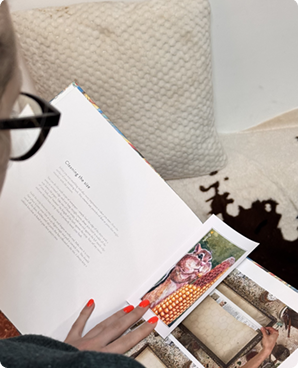 Open book on a couch with printed postcards tucked between the pages